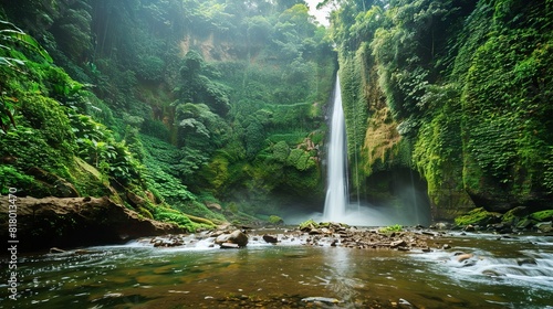 The image is of a waterfall in a jungle. A woman in a bikini is standing on a rock in the foreground. The waterfall is surrounded by green trees and plants.  