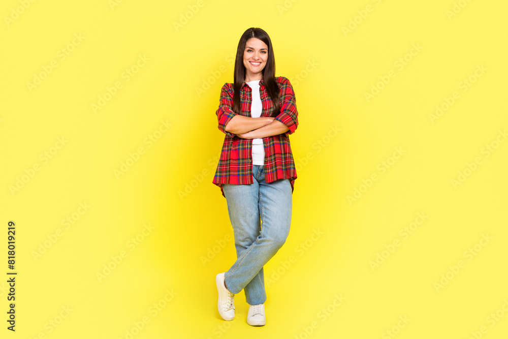 Full length photo of confident attractive lady dressed checkered shirt arms crossed empty space isolated yellow color background Full length photo of confident attractive lady dressed checkered shirt arms crossed empty space isolated yellow color background