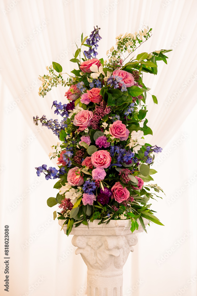 A beautiful vertical floral arrangement with greenery, pink, and purple flowers. 