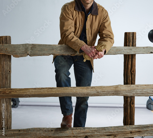 Cowboy leaning on wood split rail farm fence.  photo