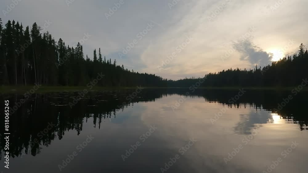 Point of view from the front of a canoe drifting forwards on a calm river that is surrounded by a dense forest of spruce trees. Lily pads float on the surface of the water.
Point of view from the front of a canoe drifting forwards on a calm river that is surrounded by a dense forest of spruce trees. Lily pads float on the surface of the water.