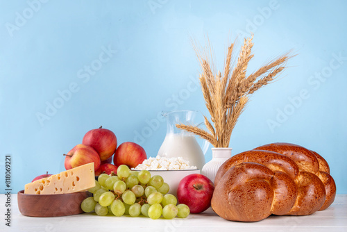 Happy Shavuot holiday background with summer red apples, wheat, grapes, dairy products - cheese, cottage cheese, milk or cream, copy space for text