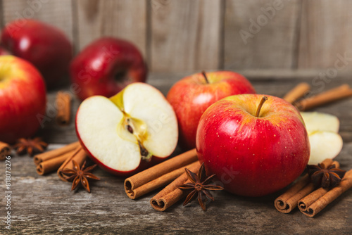 Apples with cinnamon on a textured wooden background. Fragrant red spiced apples with cinnamon sticks and star anise. Apple slices with spicy spices. Place for text. Copy space. Harvesting. Fruits. 