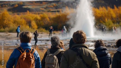 A group of tourists gathered around a geyser just before it erupts