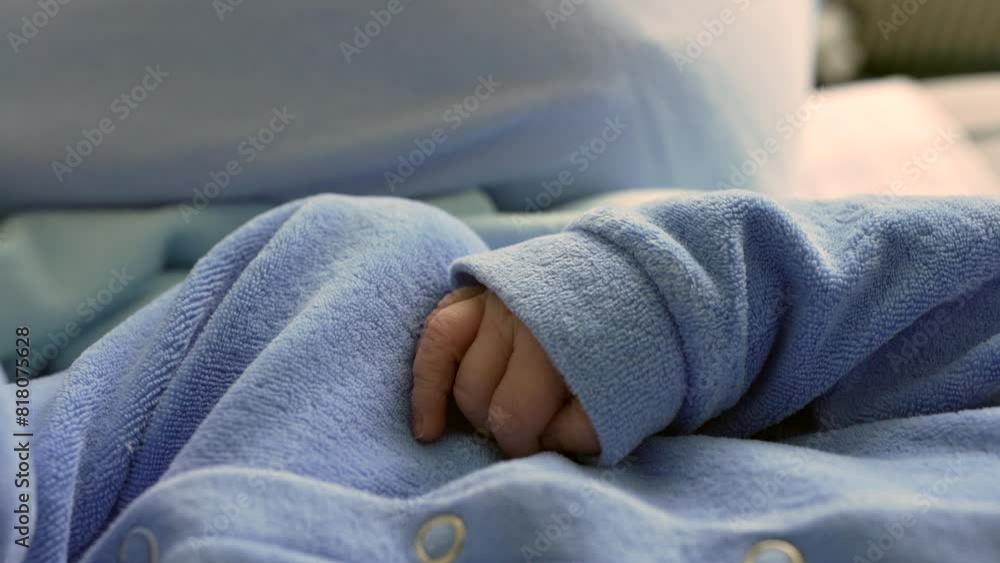 Close-up of a newborn baby's hand gently tucked inside a soft blue onesie sleeve. the delicate and peaceful moment, highlighting the innocence and purity of early infancy in a cozy environment Close-up of a newborn baby's hand gently tucked inside a soft blue onesie sleeve. the delicate and peaceful moment, highlighting the innocence and purity of early infancy in a cozy environment