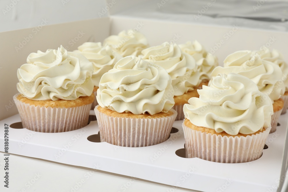 Tasty cupcakes with vanilla cream in box, closeup Tasty cupcakes with vanilla cream in box, closeup