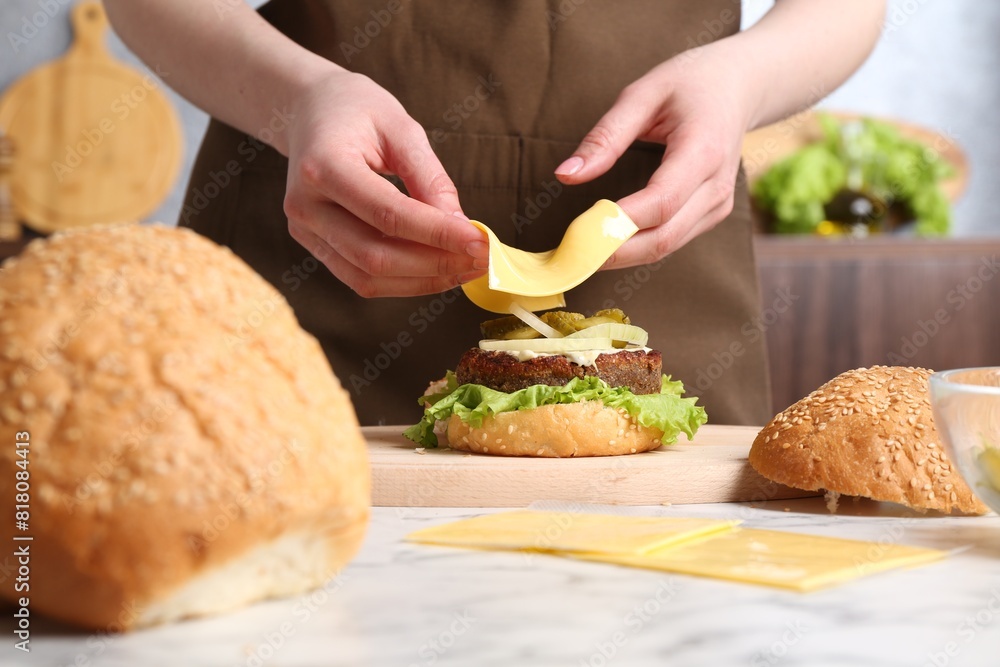 Woman making delicious vegetarian burger at white marble table, closeup Woman making delicious vegetarian burger at white marble table, closeup
