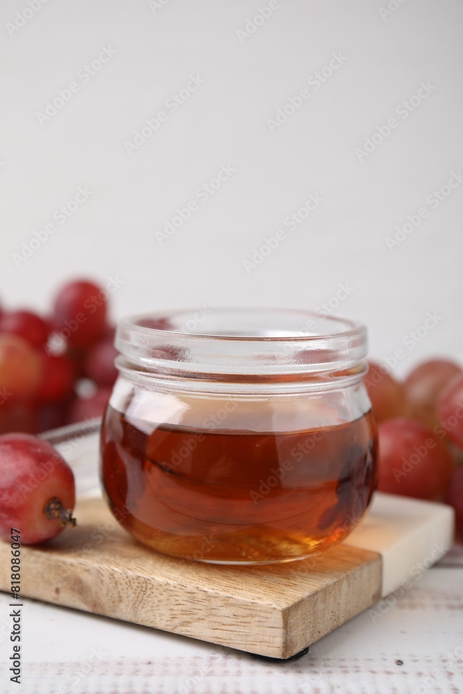Wine vinegar in glass jar and grapes on light wooden table Wine vinegar in glass jar and grapes on light wooden table