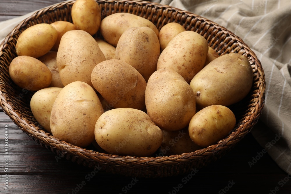 Raw fresh potatoes in wicker basket on wooden table Raw fresh potatoes in wicker basket on wooden table