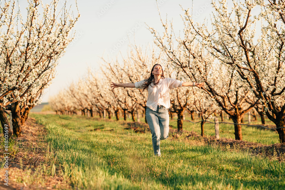 Cheerful young woman in jeans is running free through an almond orchard. Cheerful young woman in jeans is running free through an almond orchard.