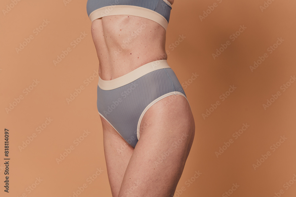 Cropped photo of attractive sporty slim body grey lingerie no filter elderly woman isolated on beige color background Cropped photo of attractive sporty slim body grey lingerie no filter elderly woman isolated on beige color background