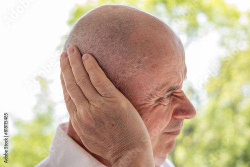 mature man holds painful ear, hearing loss, face close-up, medical concept, hearing control, middle ear inflammation, otitis media