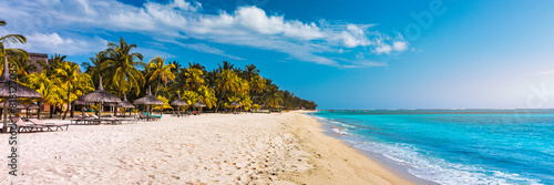 A beach with palm trees and umbrellas on Le morne Brabant beach in Mauriutius. Tropical crystal ocean with Le Morne beach and luxury beach in Mauritius. Le Morne beach with palm trees, white sand photo