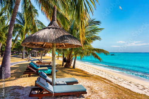 A beach with palm trees and umbrellas on Le morne Brabant beach in Mauriutius. Tropical crystal ocean with Le Morne beach and luxury beach in Mauritius. Le Morne beach with palm trees, white sand © daliu