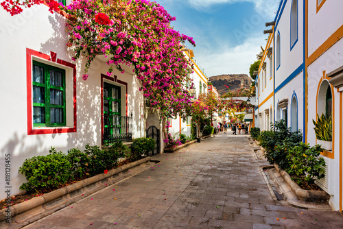 Street with blooming flowers in Puerto de Mogan  Gran Canaria  Spain. Favorite vacation place for tourists and locals on island. Puerto de Mogan with lots of bougainvillea flowers  Canary Island.