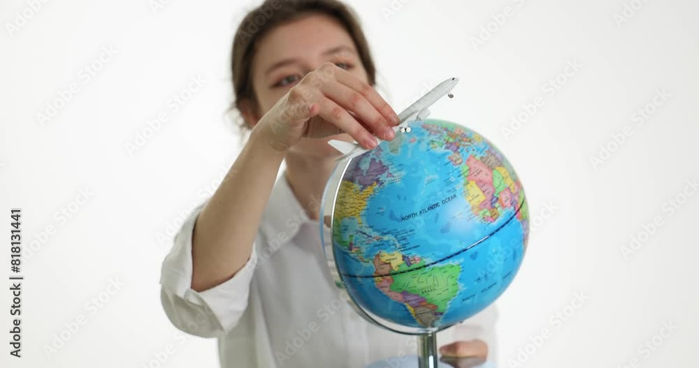 Woman plays with toy airplane sitting by Earth globe dreaming about travelling against white wall. Travel agency concept and flights to countries slow motion Woman plays with toy airplane sitting by Earth globe dreaming about travelling against white wall. Travel agency concept and flights to countries slow motion