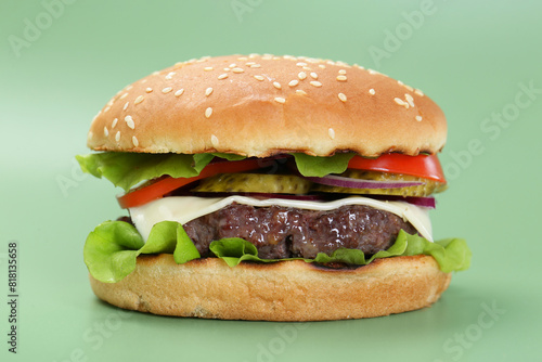 Burger with delicious patty on green background, closeup