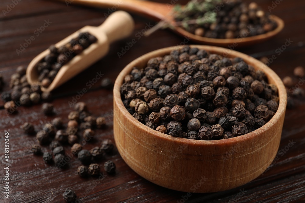 Aromatic spice. Black pepper in bowl and scoop on wooden table, closeup Aromatic spice. Black pepper in bowl and scoop on wooden table, closeup