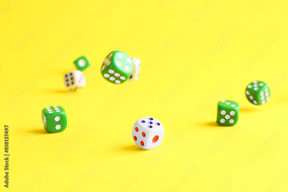 Many color game dices falling on yellow background Many color game dices falling on yellow background
