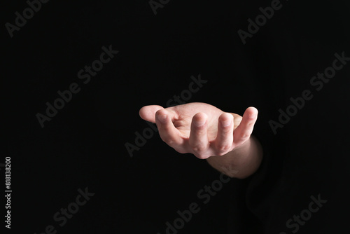 Man holding something in his hand on black background, closeup
