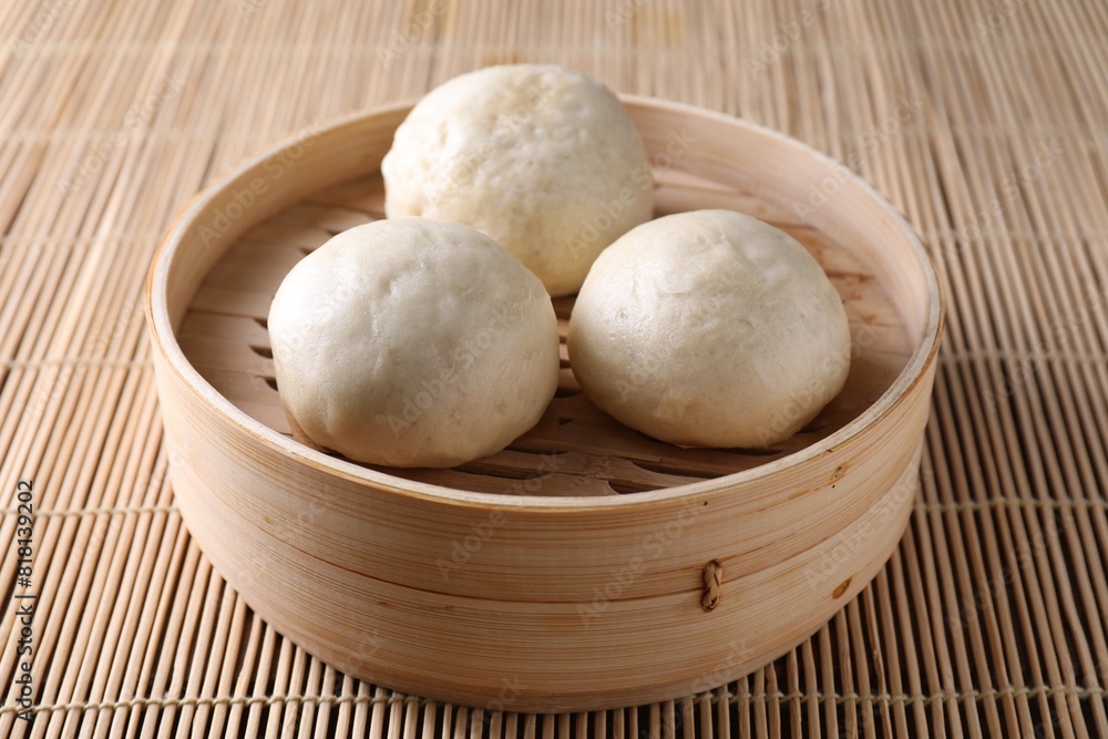 Delicious Chinese steamed buns on bamboo mat, closeup Delicious Chinese steamed buns on bamboo mat, closeup