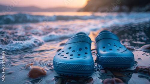 A pair of Crocs are laying on the beach at sunset photo