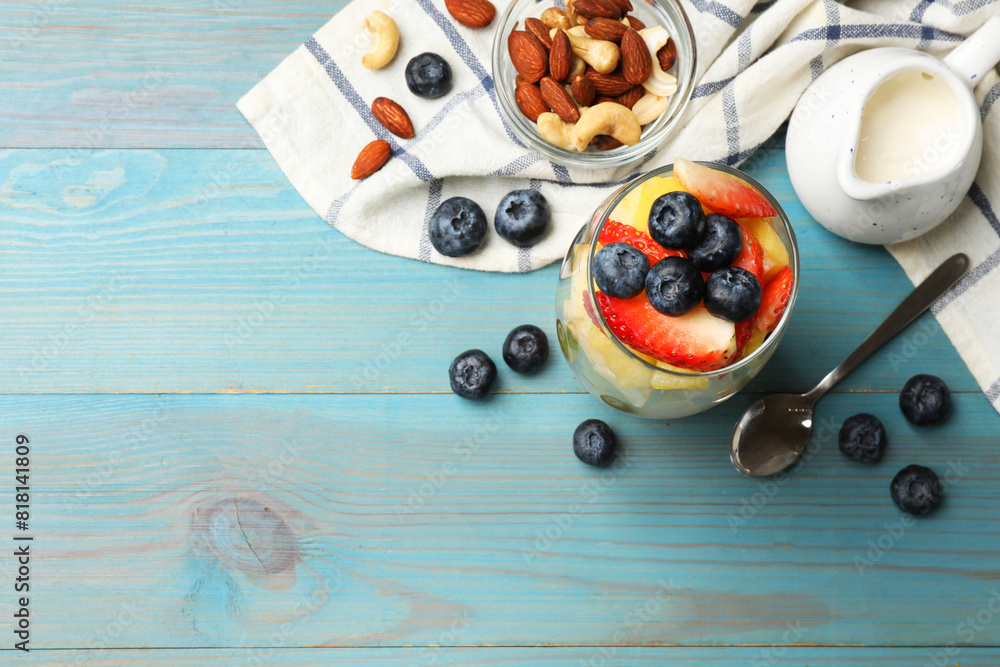 Delicious fruit salad, fresh berries and nuts on light blue wooden table, flat lay. Space for text