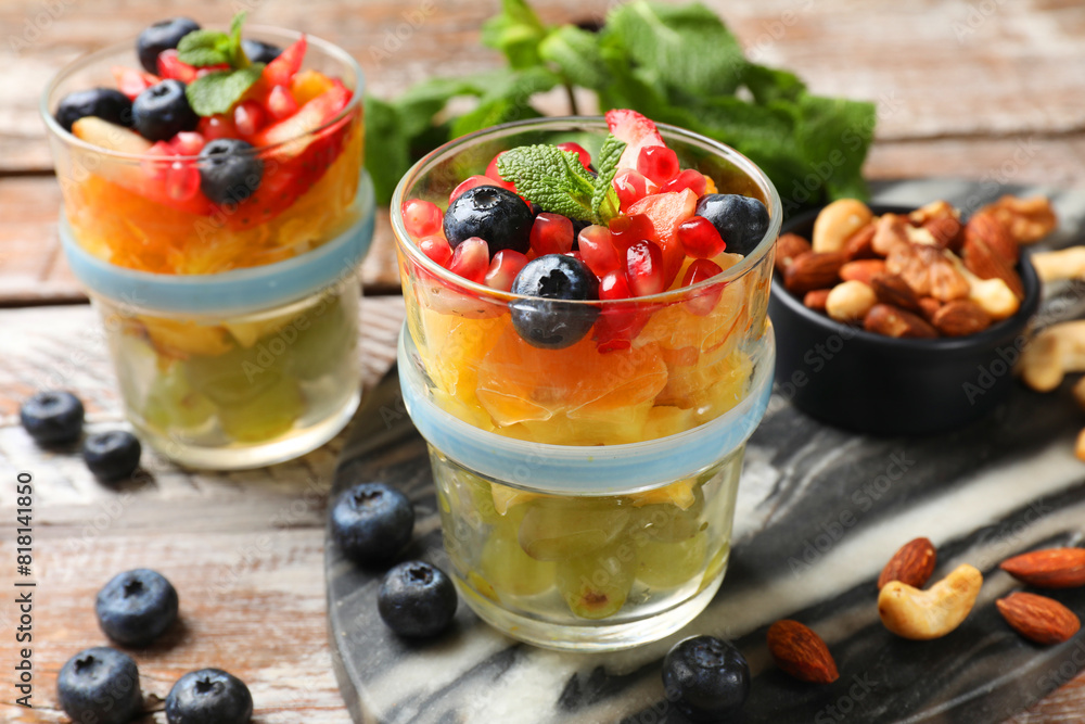 Delicious fruit salad, fresh berries, mint and nuts on wooden table Delicious fruit salad, fresh berries, mint and nuts on wooden table