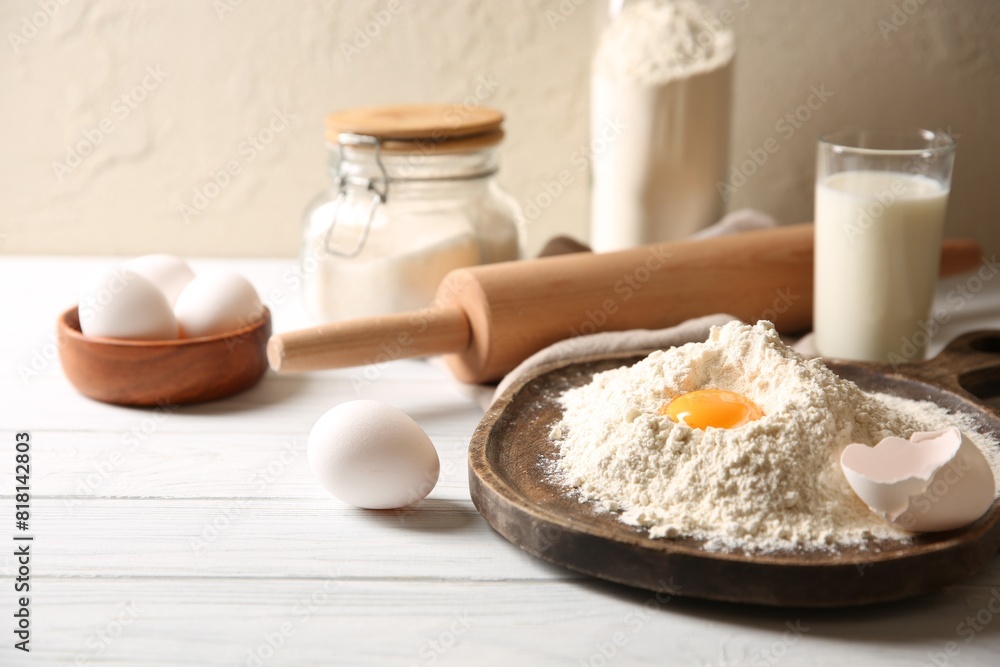 Making dough. Pile of flour with yolk, rolling pin and eggs on white wooden table, closeup Making dough. Pile of flour with yolk, rolling pin and eggs on white wooden table, closeup