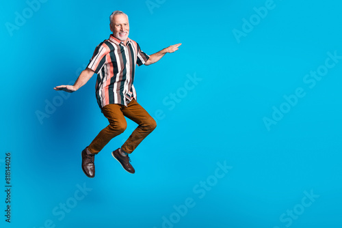 Photo of positive smiling retired man wear striped stylish clothes fly air blank space isolated on blue color background