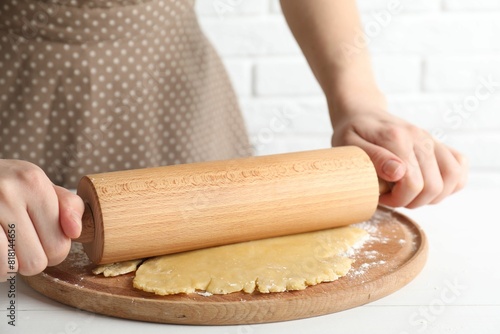 Making shortcrust pastry. Woman rolling raw dough at white wooden table, closeup