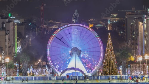 Ferris wheel inside the traditional Christmas event at Parque Eduardo VII timelapse in the city of Lisbon in Portugal. People ice skating near Christmas tree. View from above photo