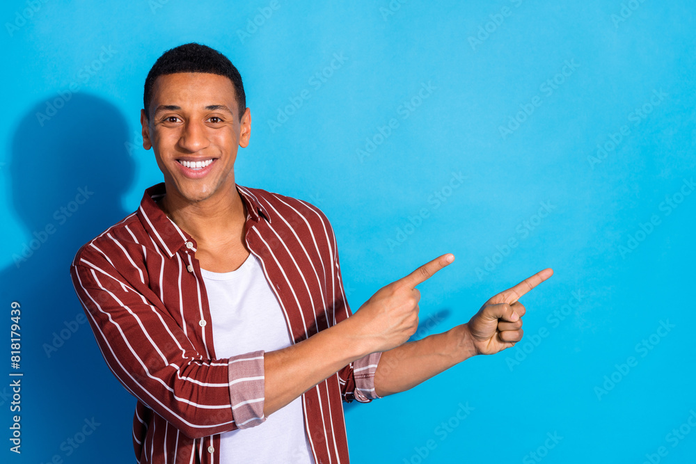 Portrait of toothy beaming man dressed striped shirt over white t-shirt directing at sale empty space isolated on blue color background Portrait of toothy beaming man dressed striped shirt over white t-shirt directing at sale empty space isolated on blue color background