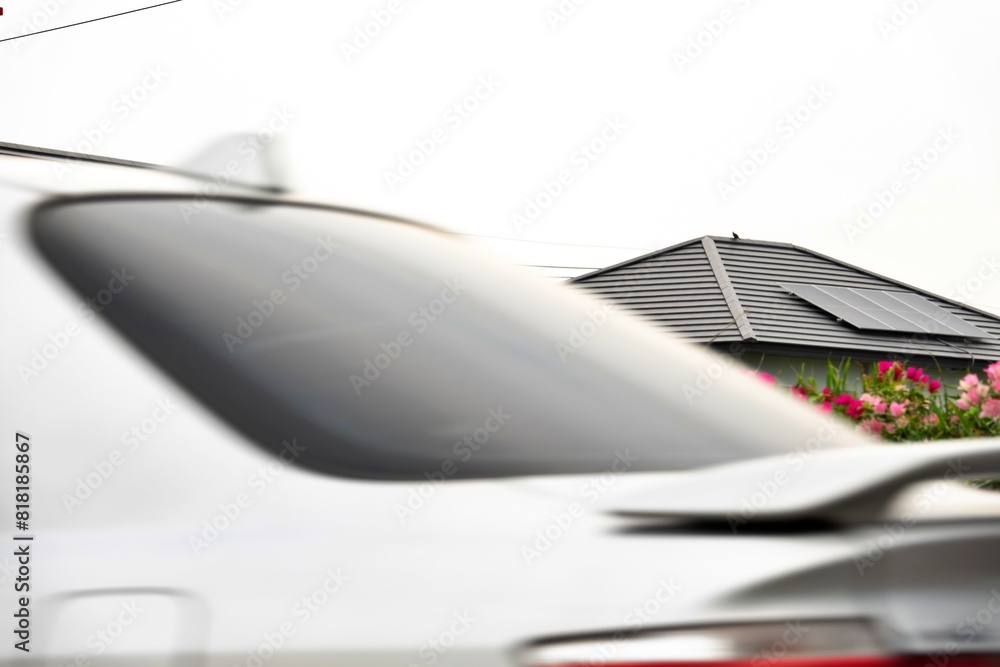 Fototapeta premium A car is parked in front of a house with a solar roof. Solar roof house