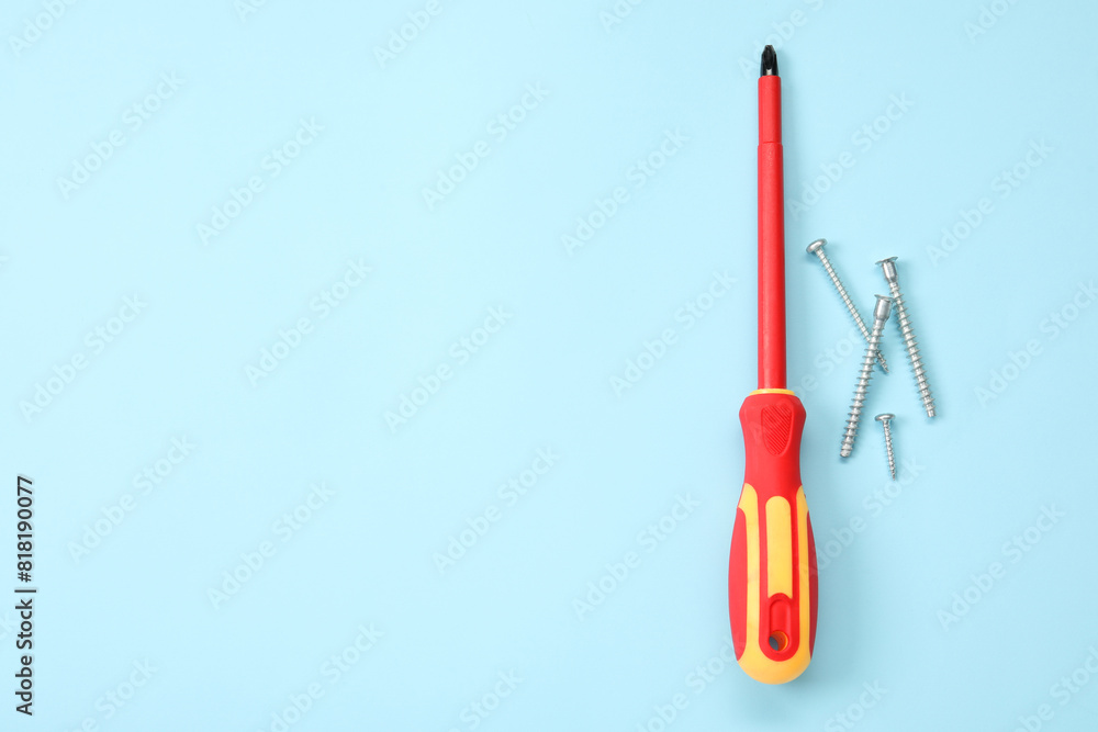 Screwdriver with red handle and screws on light blue background, flat lay. Space for text Screwdriver with red handle and screws on light blue background, flat lay. Space for text