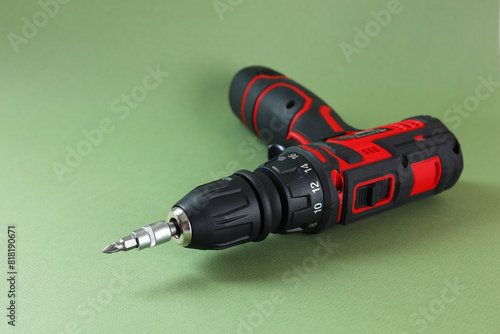 Modern electric screwdriver on pale green background