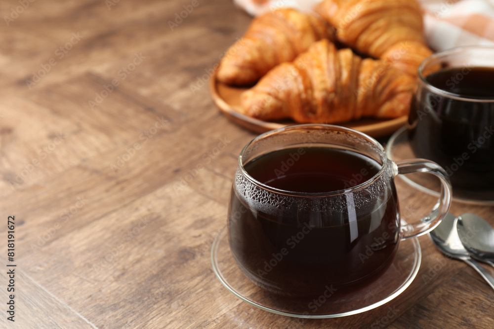 Obraz premium Hot coffee in glass cup on wooden table, closeup. Space for text