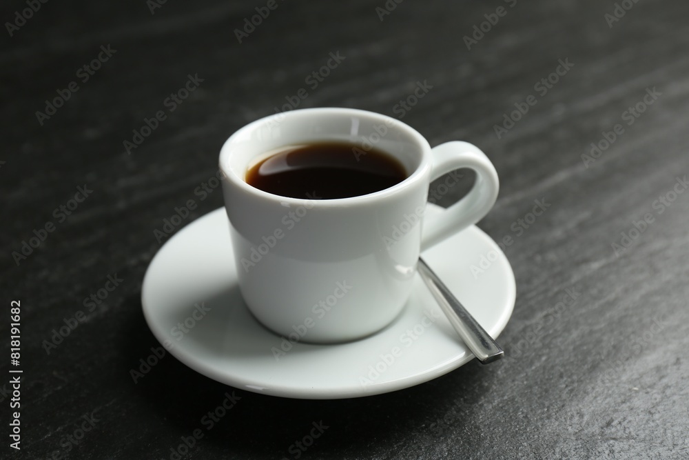 Hot coffee in cup and saucer on dark textured table, closeup