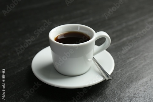 Hot coffee in cup and saucer on dark textured table, closeup