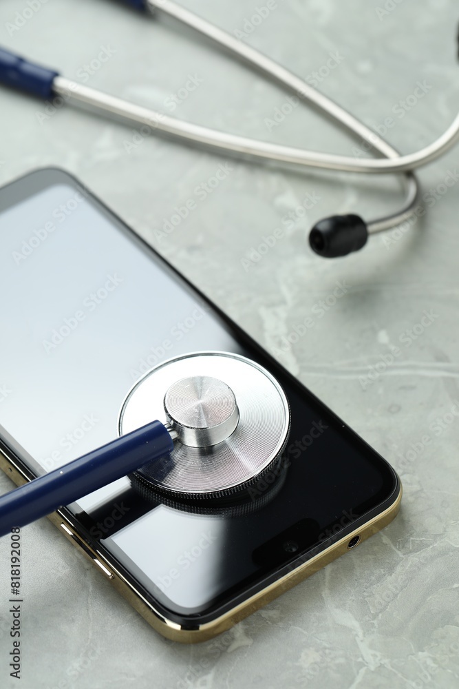 Modern smartphone and stethoscope on grey table Modern smartphone and stethoscope on grey table