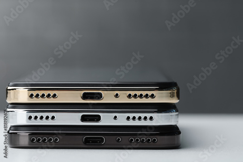 Stack of modern smartphones on white table, closeup. Space for text