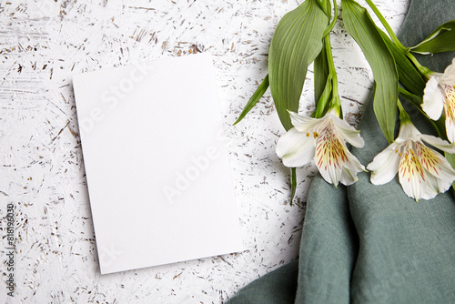 Blank vertical card mockup with Alstroemeria flowers and teal fabric on white textured background © mikeosphoto