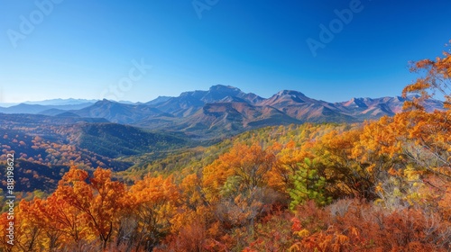 A majestic mountain range in autumn  with colorful foliage  clear blue skies  and a peaceful valley below  showcasing the beauty of nature in the fall season