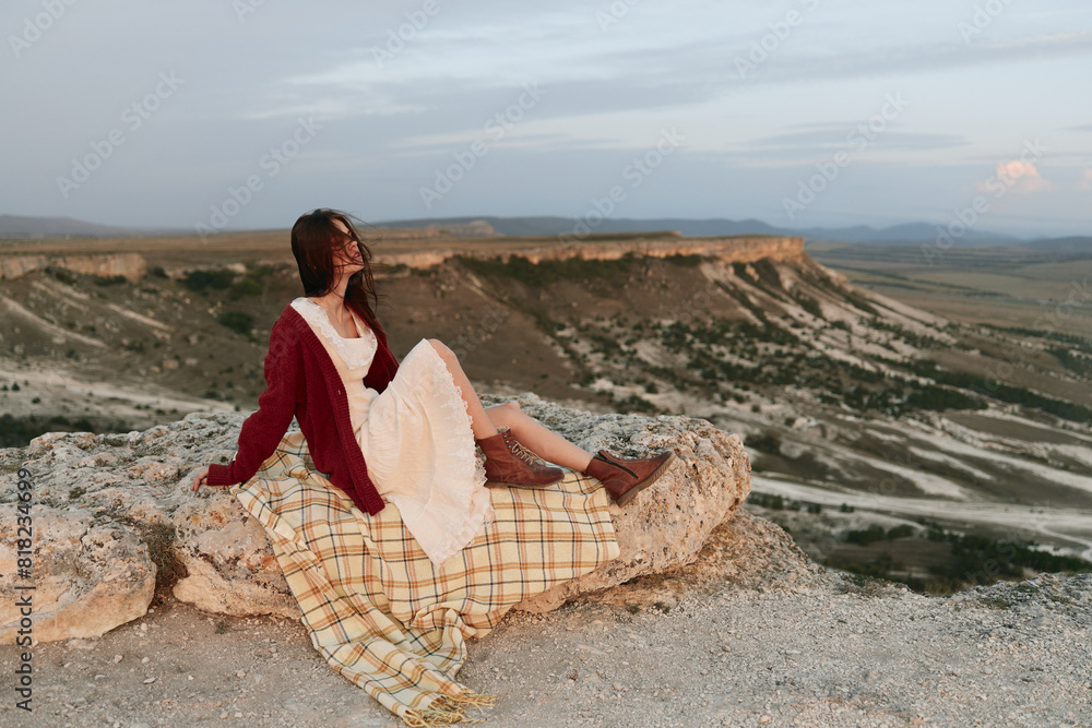 Woman sitting on top of rock enjoying mountain view in the wilderness nature beauty travel adventure trip concept Woman sitting on top of rock enjoying mountain view in the wilderness nature beauty travel adventure trip concept