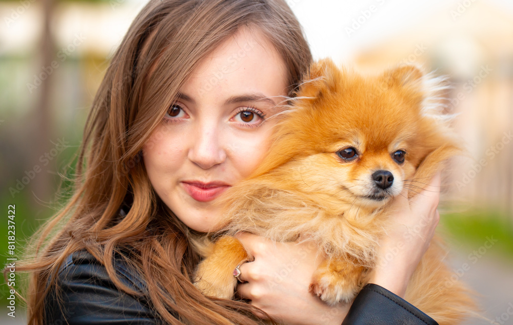 Beautiful young girl with a dog in her arms. Love to the animals. Pet on a walk. Animal protection. Pomeranian Spitz. Beautiful young girl with a dog in her arms. Love to the animals. Pet on a walk. Animal protection. Pomeranian Spitz.