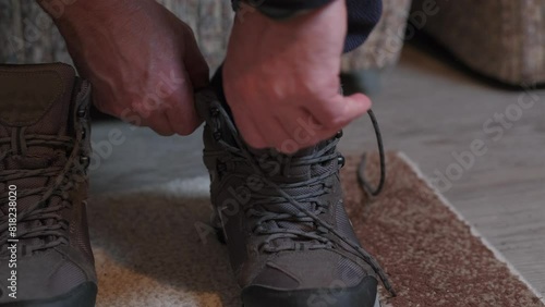 Person laces up hiking winter boots indoors. Close up of man put on trackers, and preparing himself