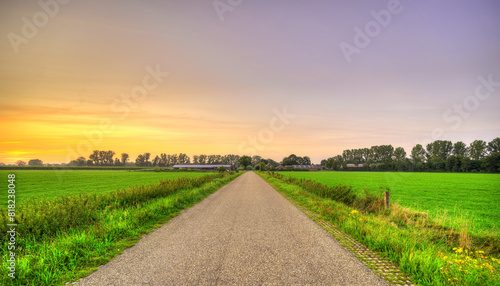Sunset falls over an empty country road in a rural landscape in The Netherlands. photo