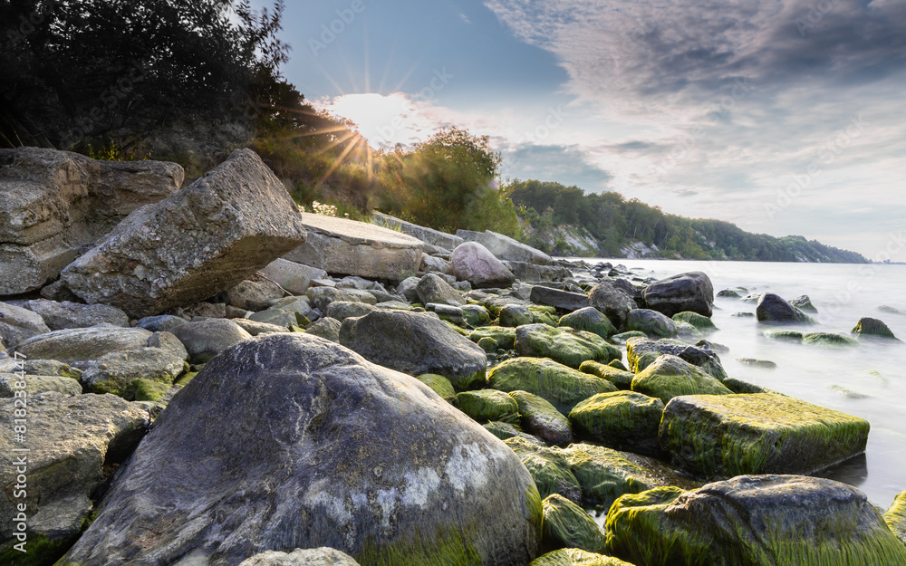 Stones covered with moss on the background of the sunset on the Baltic coast