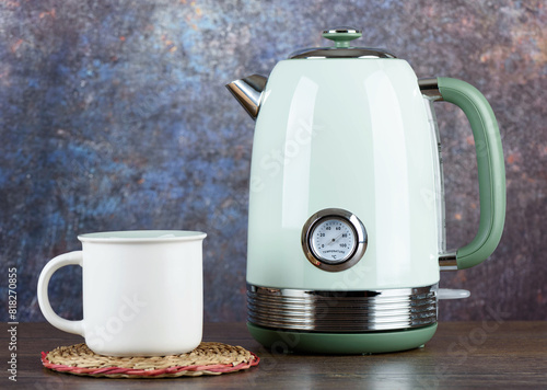 Trendy electric kettle on kitchen table with cup.