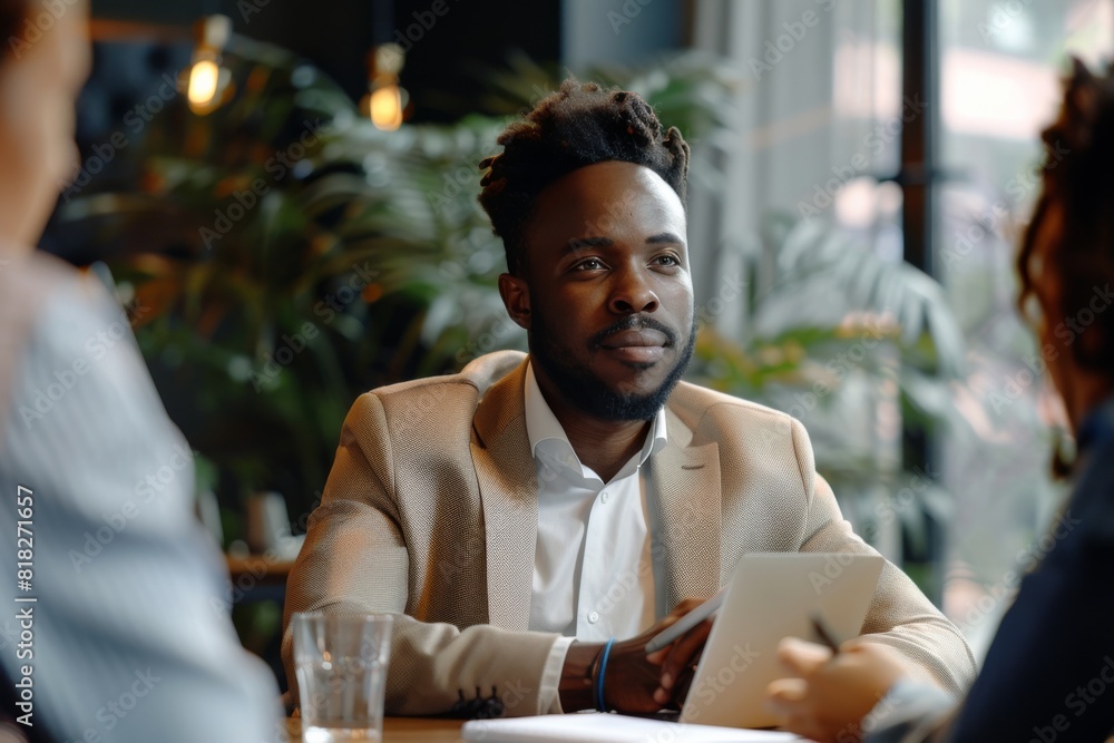 A stylish man with a contemplative expression participates in a business meeting in a modern café setting A stylish man with a contemplative expression participates in a business meeting in a modern café setting